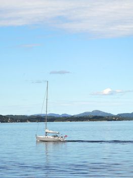 Yacht sailinng past Norway coastline near the Bergen