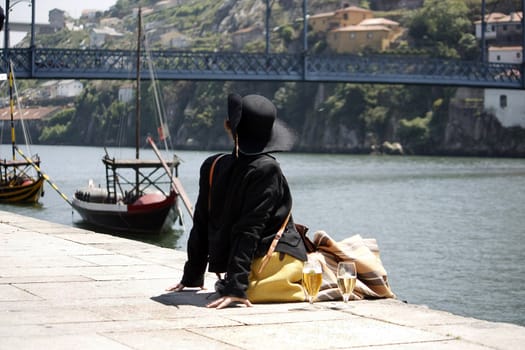Lady in traditional clothing apreciating the river view with boats and bridge.