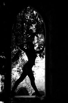 View of the figure of a young woman in silhouette over an arc.