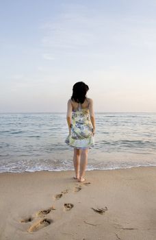 Young woman with dress tries the water on a beach.