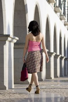 Young woman with pink and brown dress walking on the city.