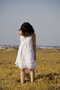 Young woman with white dress surrounded with yellow flowers.