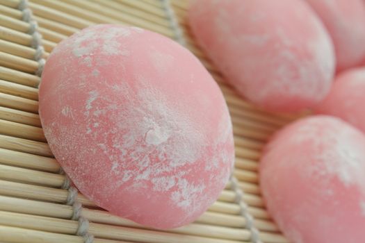 Closeup of pink japanese rice cakes on bamboo mat