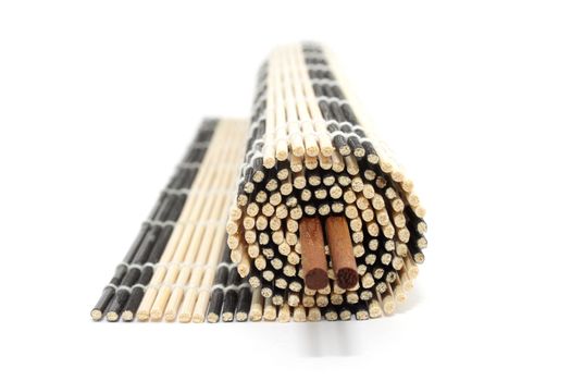 Rolled bamboo mat with a pair of chopsticks isolated on white background