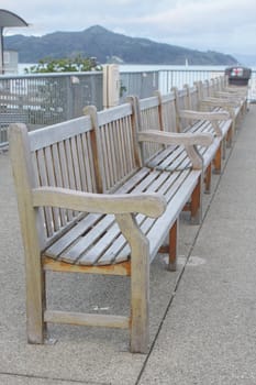 Row of wooden benches on wharf with a mountain at background