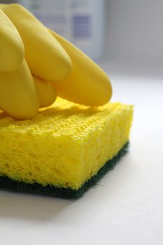 Yellow rubber gloves and yellow sponge at the kitchen table