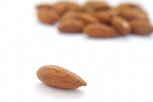 A single almond and a group of almonds on background on white