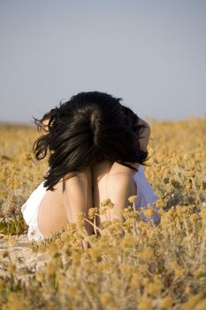 Young woman with white dress surrounded with yellow flowers.