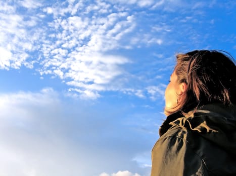 headshot, shoulder shot of a girl watching the cloudy sky.