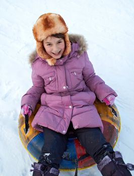 child riding color covered inner tube down snow cover hill at speed