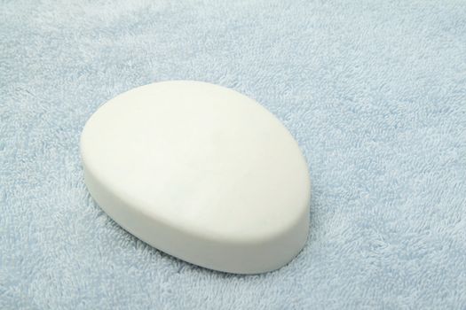 Single bar of white soap on the light blue towel