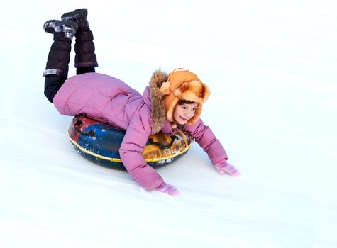 child riding color covered inner tube down snow cover hill at speed