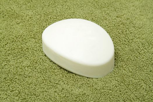 A bar of white soap on green bath towel