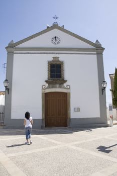 view of a young girl standing to the front of a small chappel.