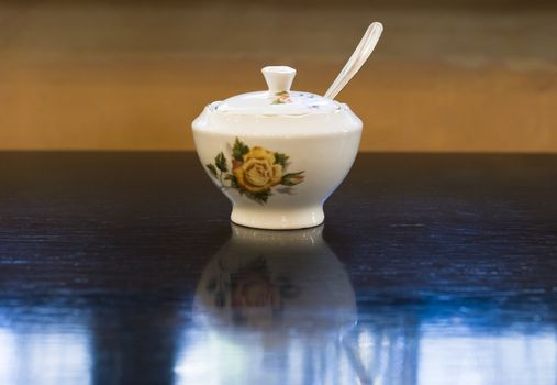 Vintage style chineese porcelain sugar bowl on table in retro cafe.