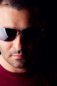 Close detail view of a young male man with dark shades  isolated on a black background.
