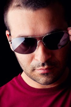 Close detail view of a young male man with dark shades isolated on a black background.