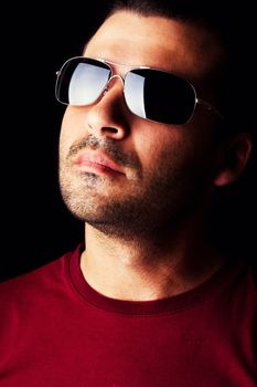 Close detail view of a young male man with dark shades  isolated on a black background.
