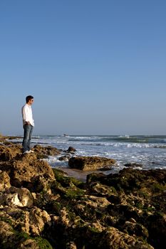 View of a young man on the shoreline enjoying the sea.