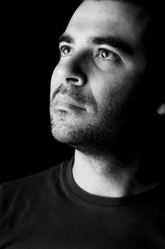 Close detail view of a young male man looking up isolated on a black background.