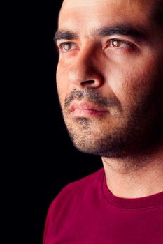 Close detail view of a young male man with a serious look isolated on a black background.