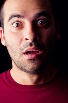 Close detail view of a surprised young male man isolated on a black background.
