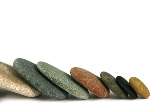 Seven pebbles in line, over white