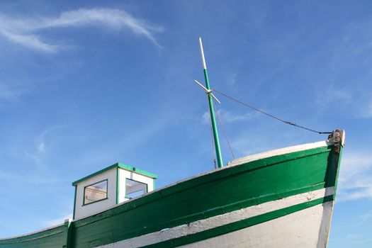 Green old fishing boat, under a blue sky