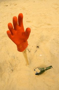 Assistance needed, hanging glove and bottle in the sand