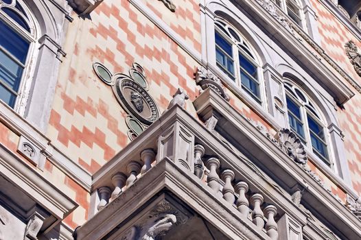 Front of an historical building with balcony, windows and friezes