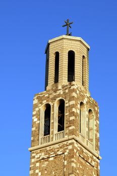 Top of high stoned bell tower against blue sky