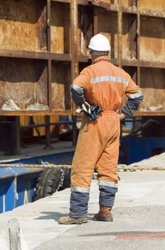 Workman with safety helmet controlling the laying of a metallic structure