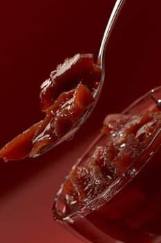macro picture: spoon of candied fruits over red