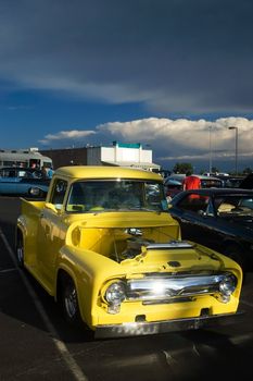 A classic 50s yellow Ford hotrod truck captured at a car show