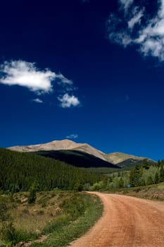 A dirt road in Rural Colorado leads to the Rocky Mountains along the Continental Divide