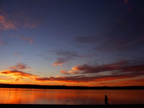 Sunrise on a lake with a person walking