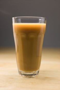 Big glass of hot coffee with milk on a wooden table