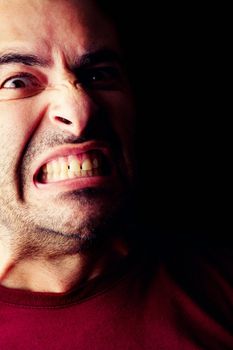 Close detail view of a furious young male man isolated on a black background.