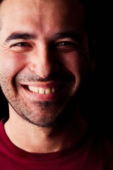 Close detail view of a happy young male man isolated on a black background.