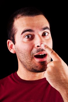 Close detail view of a funny young male man with finger on nose  isolated on a black background.