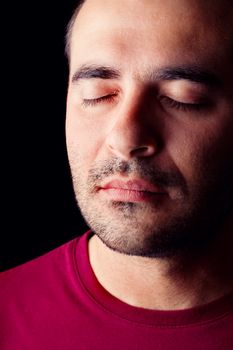 Close detail view of a sleepy young male man isolated on a black background.