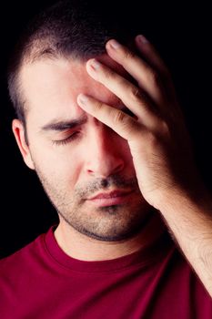 Close detail view of a young male man with a headache isolated on a black background.