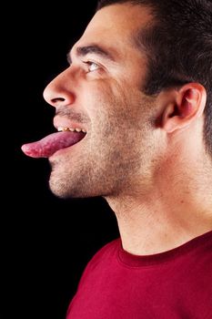 Close detail view of a young male man with tongue out isolated on a black background.