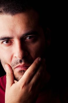 Close detail view of a thinking young male man isolated on a black background.