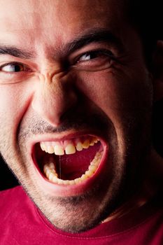 Close detail view of a angry young male man isolated on a black background.