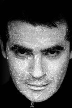 Close up view of a man looking at the camera with the face full of flour.