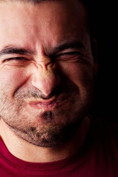 Close detail view of a young male man holding breath isolated on a black background.