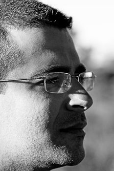 Closeup shot of the side of the face of a young man with glasses, with a serious expression.