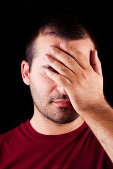 Close detail view of a embarrassed young male man isolated on a black background.