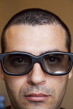 Close view of the face of a man with dark thick glasses.